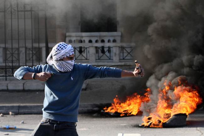 A Palestinian protester uses a slingshot to throw stones during clashes with Israeli security forces at the main entrance of the West Bank city of Bethlehem on Friday. New violence erupted in the West Bank the day before with four Palestinian attackers shot dead by Israeli forces, as Israel recoiled over a video showing Jewish extremists celebrating a Palestinian toddler's death. (AFP-Yonhap)