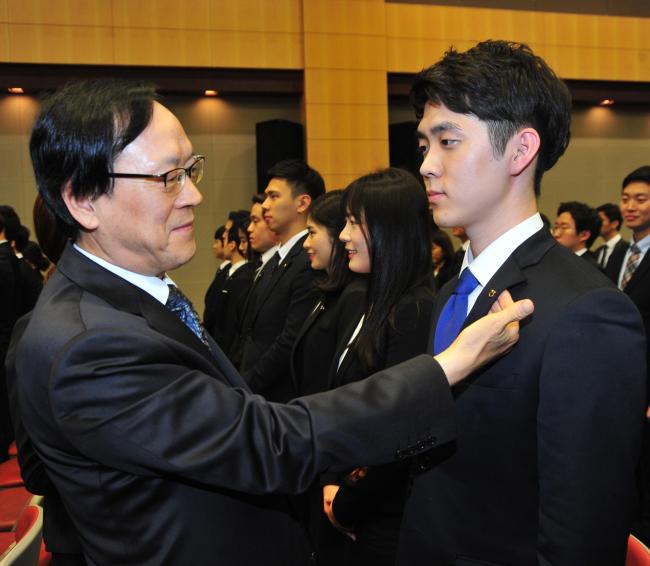 김용환<왼쪽> NH농협금융 회장이 28일 농협 본부 대강당(서울 중구 새문안로)에서 농협금융 신규직원(농협은행, 농협생명보험, 농협손해보험, 농협캐피탈, NH저축은행) 236명을 대상으로 ‘꿈을 디자인 하라’는 주제로 특강을 한후 한 신입직원에게 농협배지를 달아주고 있다.