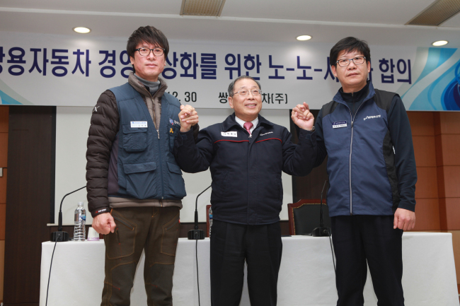 Ssangyong Motor CEO Choi Johng-sik (center), labor union leader Hong Bong-seok (right) and representative of the Ssangyong branch of Korea Metal Workers’ Union Kim Deuk-jung pose after striking a final settlement on the six-year labor dispute on Wednesday. (Ssangyong Motor)