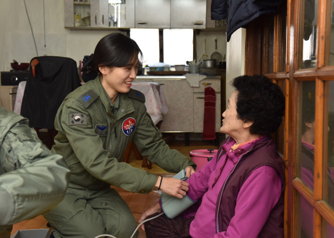 An elderly Korean woman (right) is receiving medical care from a military nurse. Yonhap