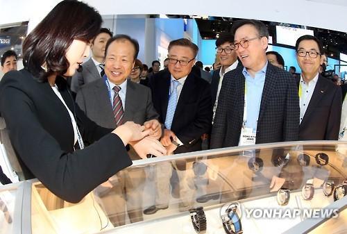 SK Telecom CEO Jang Dong-hyun(second from right), Samsung Electronics co-CEO Shin Jong-kyun (second from left), and Samsung’s mobile business chief Koh Dong-jin (center) visit the Samsung exhibition booth at the International CES trade show in Las Vegas on Wednesday. (Yonhap)