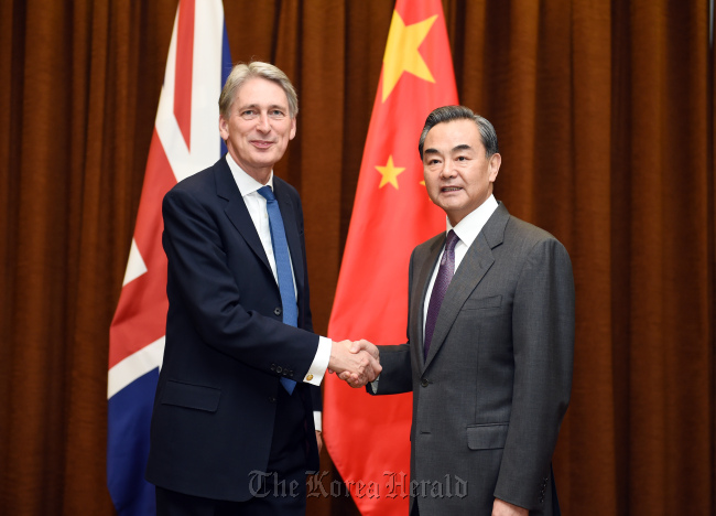Chinese Foreign Minister Wang Yi (right) shakes hands with British Foreign Secretary Philip Hammond in Beijing on Tuesday. (Xinhua-Yonhap)