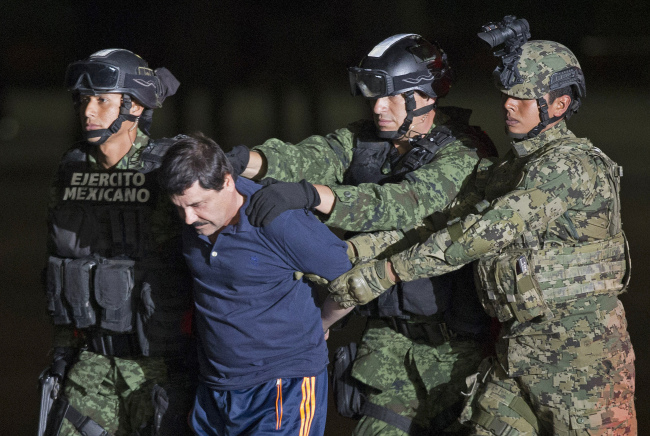 Mexican army soldiers escort drug lord Joaquin “El Chapo” Guzman to a helicopter to be transported to a maximum security prison in Mexico City on Friday.   AP-Yonhap
