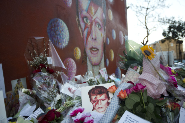 Tributes lie beside a mural of British singer David Bowie by artist Jimmy C in Brixton, south London, Tuesday, Jan. 12. AP-Yonhap