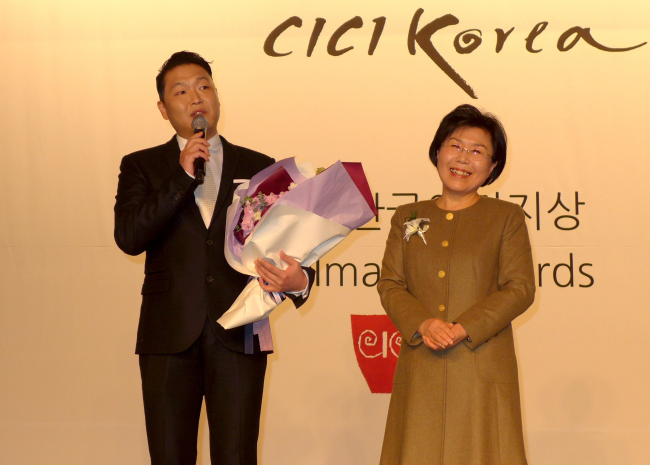 Korean singer Psy (left) accepts the Korea Image Stepping Stone Award from Choi Jung-wha, president of the Corea Image Communications Institute, at the annual award ceremony reception at Intercontinental Seoul Coex on Tuesday. Joel Lee/The Korea Herald