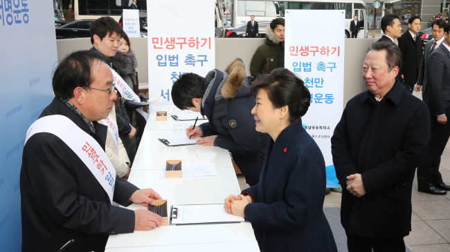 PUBLIC PETITION TO URGE BILL PASSAGE -- President Park Geun-hye (center) visits a campaign site organized by the Korea Chamber of Commerce and Industry led by chairman Park Yong-maan (right) to urge legislators to pass a set of bills on labor reform and economic recovery at the KCCI building in central Seoul. The campaign seeks to collect and submit the signatures of 10 million citizens to the National Assembly, with the aim of putting pressure on the partisan deadlock that has delayed passage of the bills for several months. KCCI