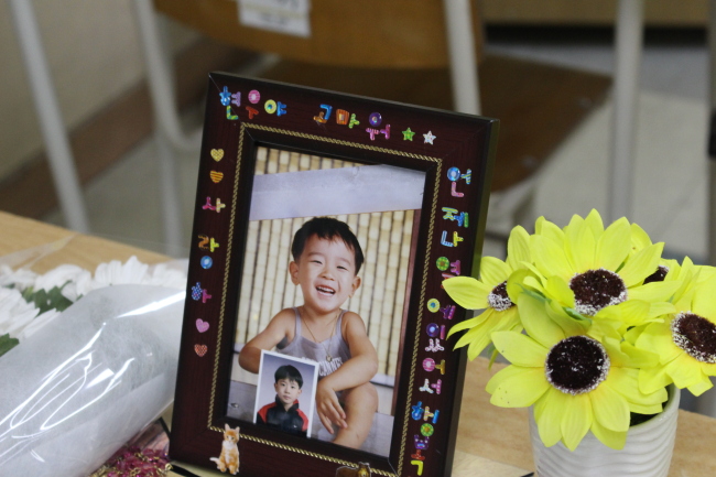 A childhood photo of Jeon Hyeon-woo is laid on his desk. The messages on the frame reads, “Hyeon-woo, I love you. Thank you for always being with me.” (Yoon Min-sik/The Korea Herald)