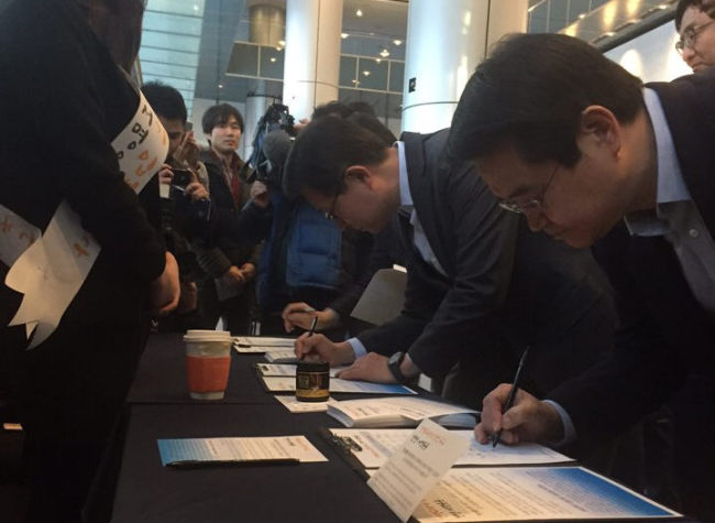 Samsung Electronics‘ network business president Kim Young-ky (left) and Samsung’s visual display division head Kim Hyun-seok sign a petition calling for prompt legislation of economic bills at the company building in Seocho, southern Seoul, Wednesday.  Yonhap