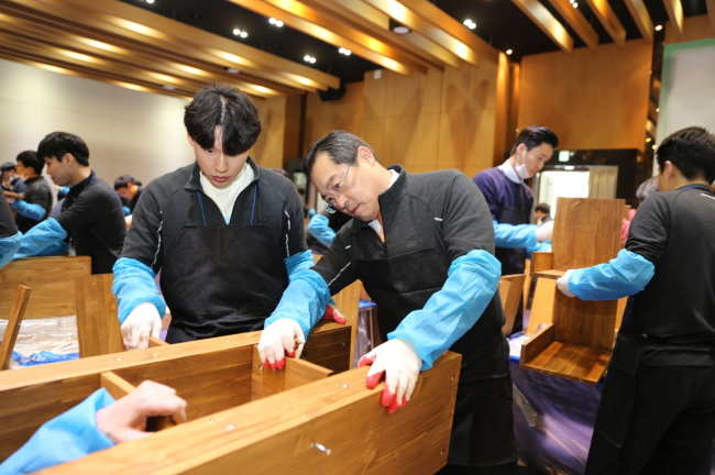 LS Group chairman Koo Ja-yeol (center) works with new employees to assemble a bookshelf at the conglomerate’s training institute in Anseong, Gyeonggi Province, Thursday. The group donated 60 bookshelves it put together along with 600 books to nearby welfare centers.   LS Group