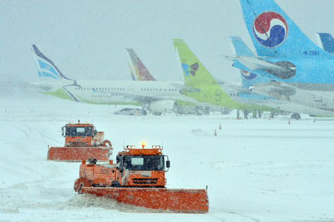 Operations are underway to clear the snow at Jeju International Airport on Monday.  Yonhap