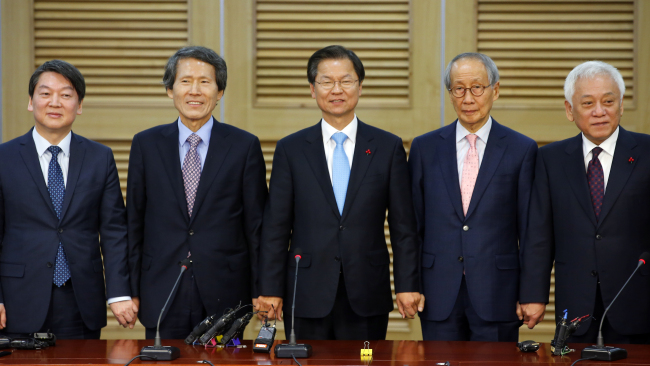 Rep. Ahn Cheol-soo (from left), co-chairman of the People‘s Party Han Sang-jin, Rep. Chun Jung-bae, co-chairman of the People’s Party Yoon Yeo-jun and Rep. Kim Han-gil hold hands for a photo session upon announcing their merge at the National Assembly on Monday.  Yonhap
