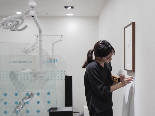 A curator installs paintings at Naver’s headquarters. (OPEN GALLERY)