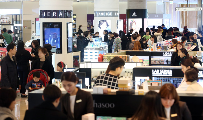 Shoppers browse through cosmetic products at the Lotte World Tower Duty Free in Seoul.  Yonhap