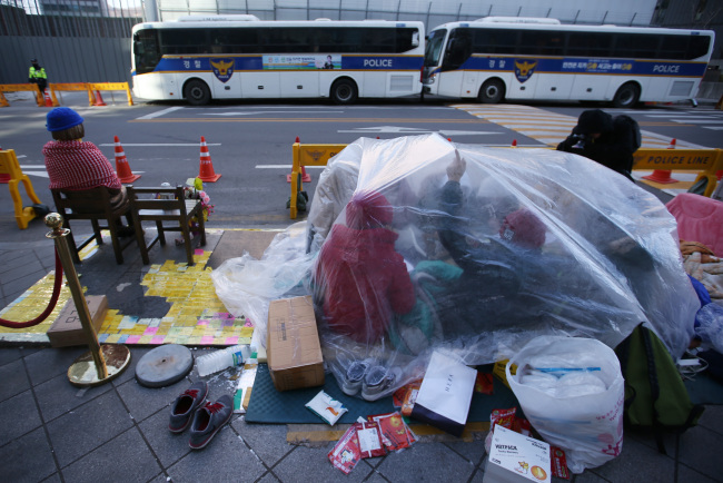Demonstrators against the Dec. 28 deal between Seoul and Tokyo try to stay warm and take cover while holding a sit-in protest next to the “comfort woman” statue.  Yonhap