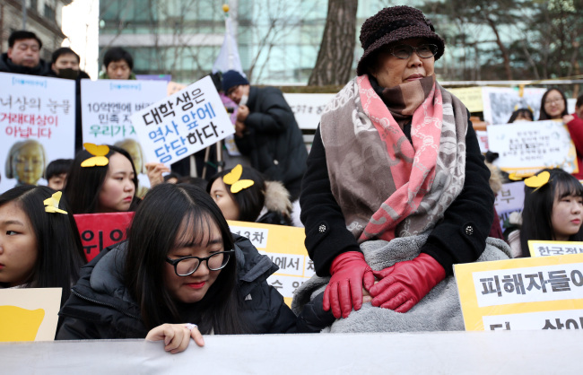 Sex slavery victim Lee Yong-su embraces the hand of a student participating in a rally in front of the Japanese Embassy in Seoul on Wednesday.  Yonhap