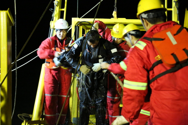 Divers from China’s Shanghai Salavage Co. and workers dispatched for the salvage operations of the Sewol ferry work on a barge off the coast of Jindo, South Jeolla Province, on Jan. 13.  Yonhap