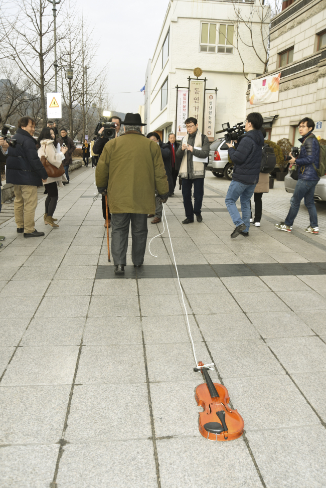 Artist Kim Tschang-yeul reenacts Nam June Paik‘s 1963 performance “Zen for Walking” on Jan. 28 at Gallery Hyundai in Seoul. (Gallery Hyundai)
