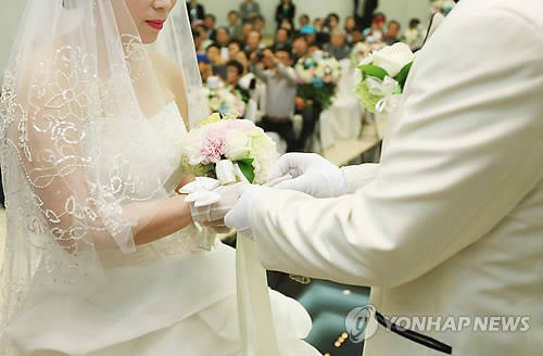 A couple gets married in a wedding ceremony. (Yonhap)