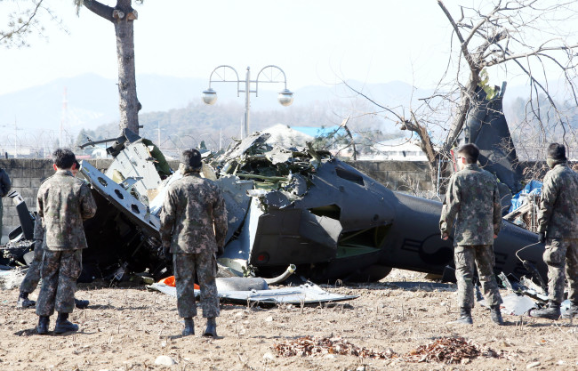 Military officials survey the wreckage of the UH-1H helicopter that crashed in a field in a village in Chuncheon, Gangwon Province, Monday. (Yonhap)