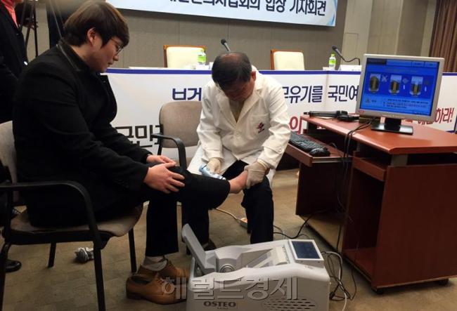 김필건 대한한의사협회장이 지난달 12일 정부에 한의사의 ‘현대 의료기기 사용문제’ 해결을 촉구하는 기자회견자리에서 ‘의료기기 사용 투쟁’ 퍼포먼스로 골밀도기 의료기기를 직접 시연하고 있다.   [사진=헤럴드경제DB]