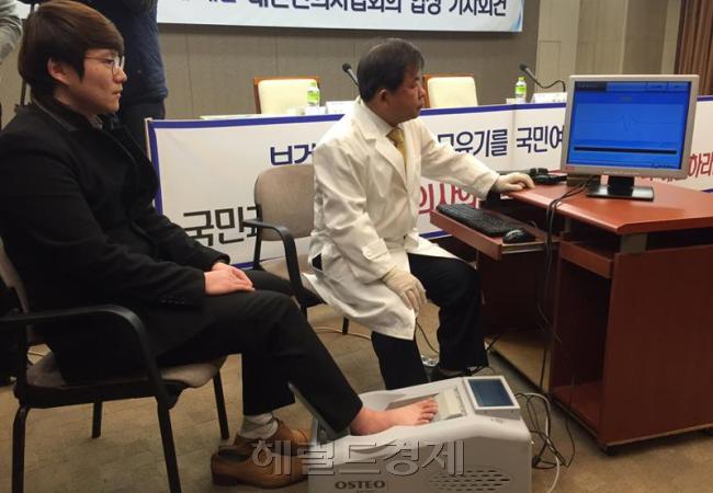 김필건 대한한의사협회장이 지난달 12일 정부에 한의사의 ‘현대 의료기기 사용문제’ 해결을 촉구하는 기자회견을 한후 ‘의료기기 사용 투쟁’ 퍼포먼스로 골밀도기 의료기기를 직접 시연하고 있다. [사진=헤럴드경제DB]