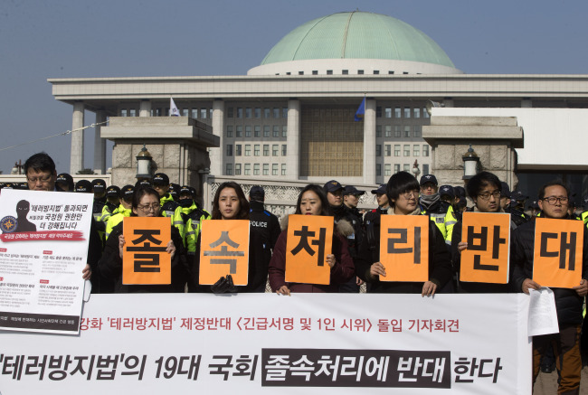 Activists hold up placards Tuesday to oppose the passage of the antiterrorism bill in front of the National Assembly building in Seoul. (Yonhap)