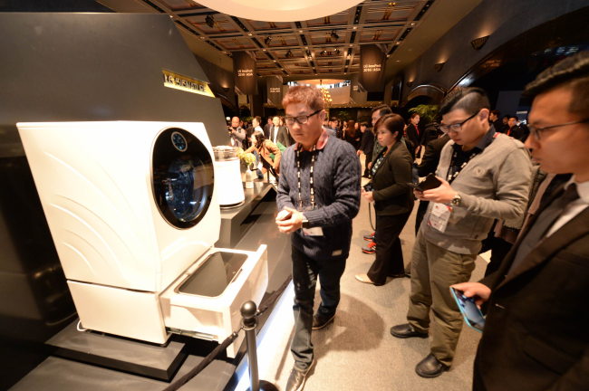 Global buyers and dealers look at LG Eelectronics‘ Signature washing machine, which features front-loading on top and a top-load washer on the bottom, at the firm’s showcase event in Korea this month. (LGE)