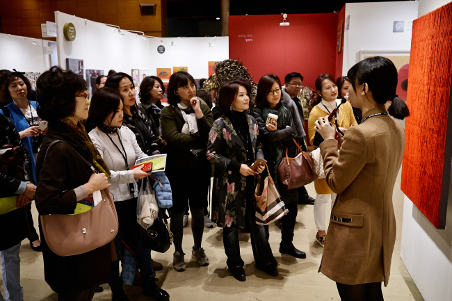 Visitors listen to an art guide during a guided tour at the Korea Galleries Art Fair 2015. (Galleries Association of Korea)