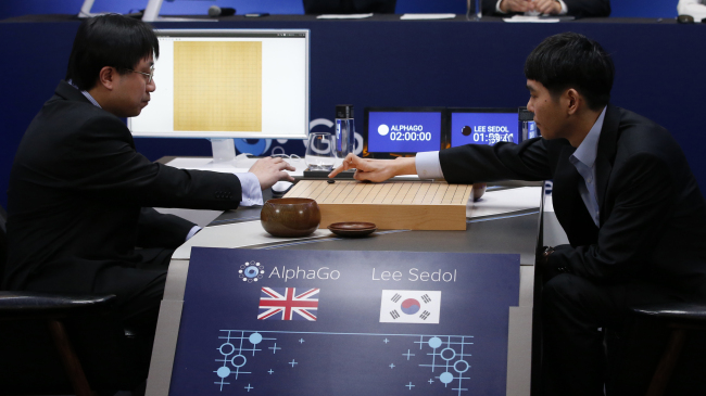 Go player Lee Se-dol (right) places the first stone against Google’s artificial intelligence program AlphaGo during the Google DeepMind Challenge Match in Seoul on Wednesday. AP-Yonhap