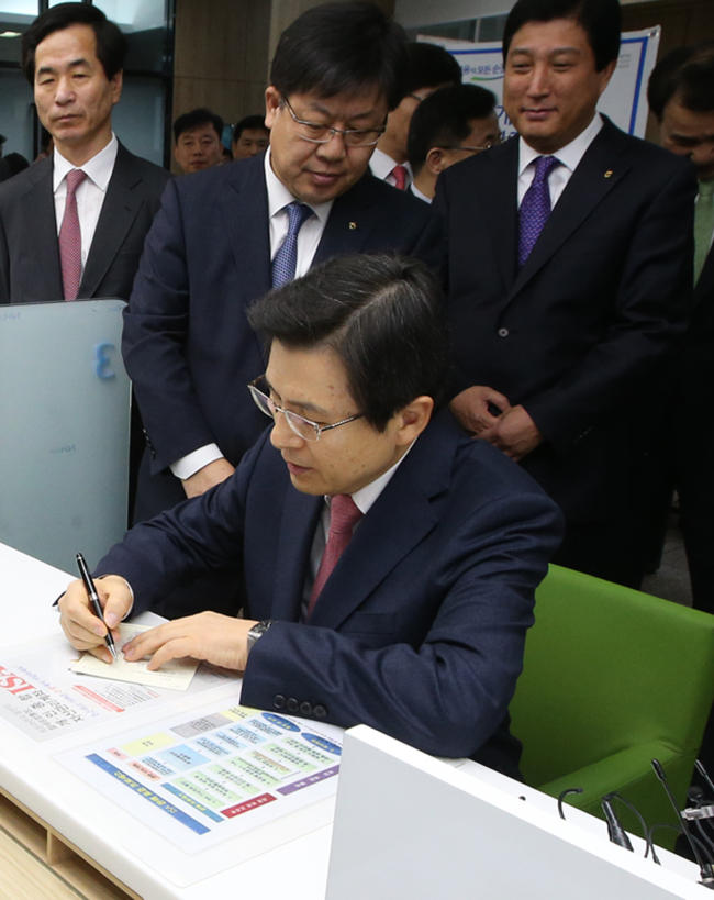 Prime Minister Hwang Kyo-ahn receives a bank account book after opening a tax-exempt individual savings account during his visit to a NongHyup Bank branch in Daejeon on Monday (Yonhap)
