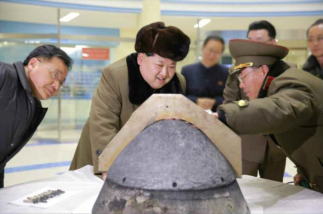 North Korean leader Kim Jong-un (middle) looks at a device presumed to be a warhead of a ballistic rocket in this photo released by North Korea’s Rodong newspaper on Tuesday. (Yonhap)