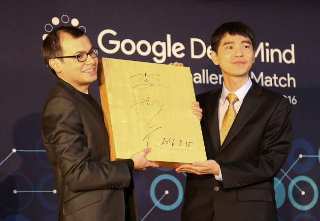 Korean Go player Lee Se-dol(right) and DeepMind CEO Demis Hassabis pose with a Go board autographed with Lee's name.(Google)