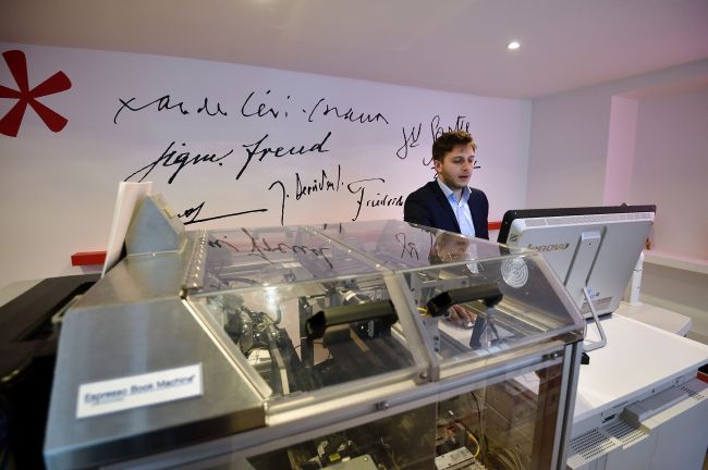 Alexandre Gaudefroy, manager of the Presses Universitaires de France (PUF) bookstore, prints out a book at the publishing house’s new bookstore in Paris on March 16, 17 years after closing their mythical bookstore at the Place de la Sorbonne. PUF opened on March 10 the new innovative space where customers can print the book of their choice within minutes. (AFP-Yonhap)
