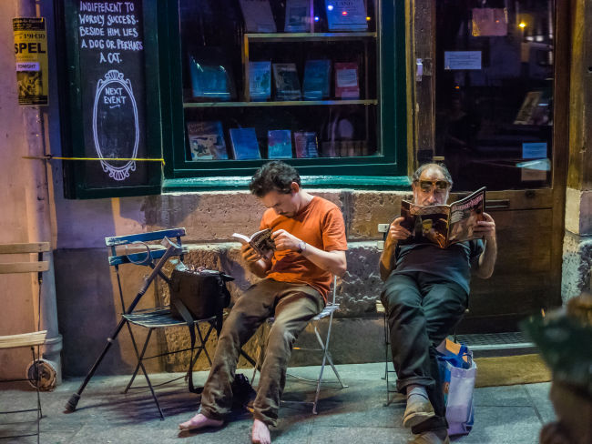 Two men read in front of a bookstore in Paris. (123rf)