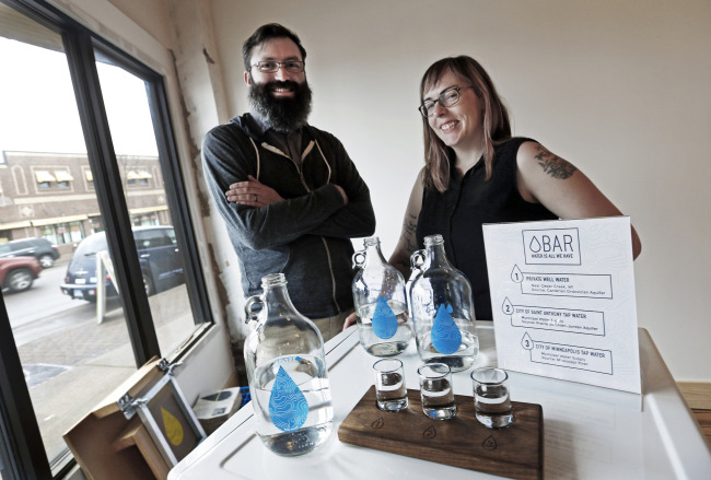 Colin Kloecker and his wife, Shanai Matteson, pose with water in growlers and glasses in the building where they are preparing to open a storefront Water Bar in northeast Minneapolis on March 16. (AP-Yonhap)