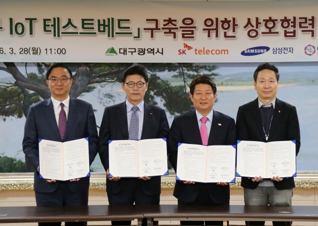 (From left) Kim Young-ky, president of Samsung Electronics’ network business, Lee Young-hee, president of SKT’s mobile network operations, Daegu Mayor Kwon Young-jin, and Kim Sun-il, president of the Center for Creative Economy and Innovation in Daegu, pose after the signing ceremony for a memorandum of understanding to build an Internet of Things test bed in Daegu. (SKT)
