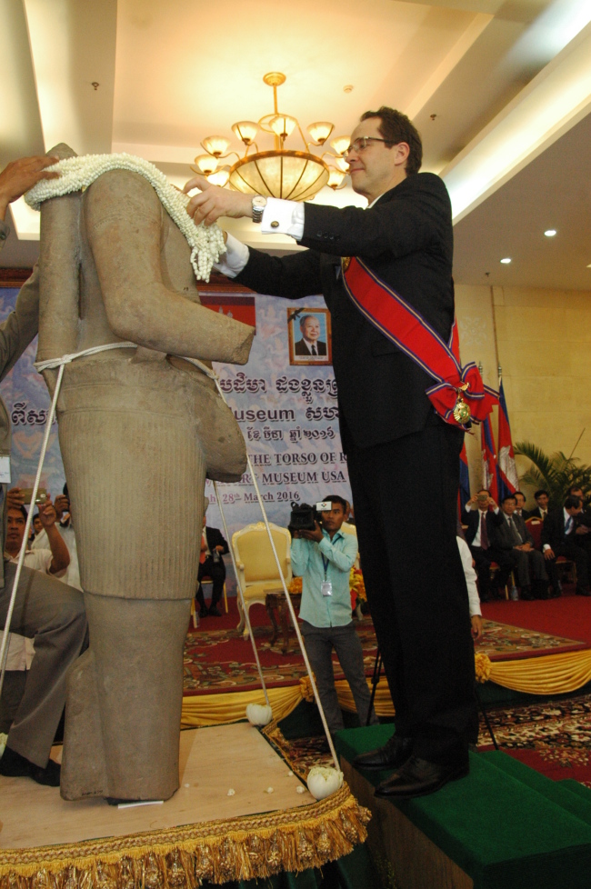 Christoph Heinrich, director of the Denver Art Museum, places a garland on the torso of Rama in Phnom Penh, Cambodia, on Monday. (Xinhua-Yonhap)