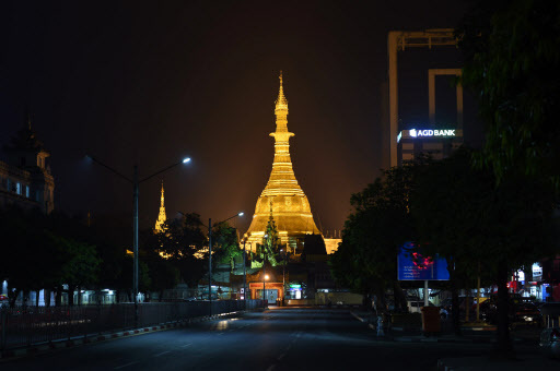The Sule Pagoda tower, newly covered with gold, glows under spotlights before dawn on March 23. (AFP-Yonhap)