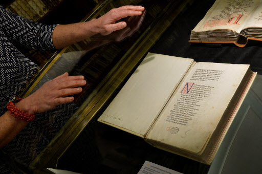A woman stands by the first printed edition of the “Divine Comedy” of Dante at the Library of the Academy of the Lincei and Corsiniana , on March 30, during a press preview of the exhibition. (AFP-Yonhap)