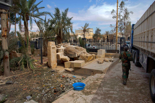 A Syrian soldier walks next to the damaged Lion of Al-Lat statue outside the museum with some broken pieces lying next to it at the entrance of the museum in the town of Palmyra in the central Homs province, Syria, on April 14. (AP-Yonhap)