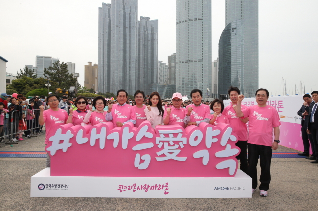 Social and corporate leaders cheer with other supporters at the Pink Ribbon Love Marathon for breast cancer awareness in Busan on Sunday. Among them are Kim Young-soo (fifth from left), head of AmorePacific’s Premium Business Unit, Mamonde spokesmodel Park Shin-hye (center) and Noh Dong-young (fifth from right), head of the Korea Breast Cancer Foundation. (AmorePacific)