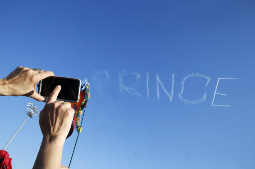 A festivalgoer takes a photo as a skywriter spells “Prince,” in honor of pop music icon Prince, at the New Orleans Jazz and Heritage Festival in New Orleans, Saturday. (AP-Yonhap)