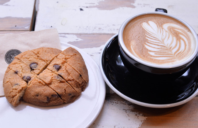 Hayley's Cafe's massive dark chocolate chip cookie (left) and an Australian-style flat white (Lee Sang-sub/The Korea Herald)