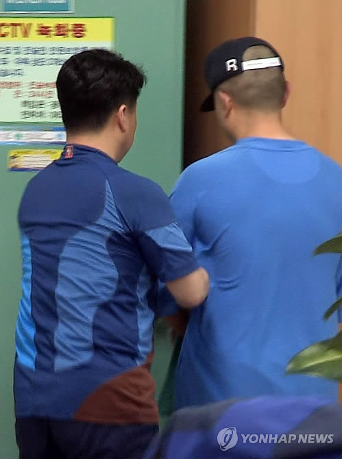 10일 광주 북부경찰서에서 아버지를 살해한 혐의로 붙잡힌 40대 남성(오른쪽)이 얼굴을 가리지 않은 채로 이동하고 있다. 이 피의자는 경찰의 권유에도 얼굴을 가리지 않겠다고 완강히 버텨 결국 얼굴이 공개됐다. (Yonhap)
