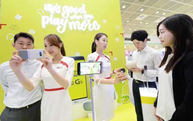 Visitors to the World IT Show, a tech trade show, use LG Electronics’ G5 smartphone at the firm’s exhibition venue. (LGE)
