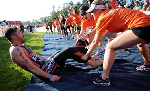 A participant takes off his swimming suit with the help of volunteer workers at the Ironman 70.3 Texas in the U.S. in 2014. (Emerson K Partners)