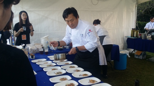 Chef Ming Tsai prepares a main dish of Amberjack sashimi, Madras curry oil and unistuffed pyogo mushroom at his tent. (Kim Hoo-ran/ The Korea Herald)