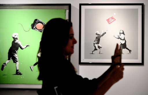 A woman takes picture on Monday of the works made by England-based graffiti artist Banksy, during the “Guerra, Capitalismo & Liberta (War, Capitalism and Freedom)” exhibition at Rome’s Palazzo Cipolla. (AFP-Yonhap)