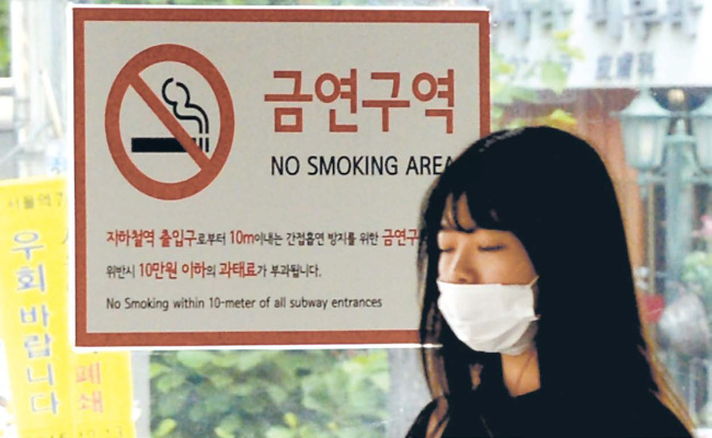 미세먼지 주의보가 내려진 31일‘ 세계 금연의 날’을 맞아 서울시내 한 지하철 역에서‘ 지하철역 10ｍ 내 금연’ 표지판 옆
으로 마스크를 쓴 시민이 걸어가고 있다. 박현구 기자/phko@heraldcorp.com