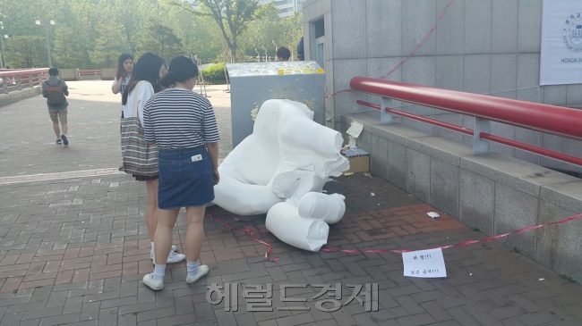 재학생과 네티즌 사이에서 논란이 벌어졌던 홍익대 정문 앞 ‘일간베스트저장소(일베)’ 상징 조형물이 1일 새벽 결국 부서졌다. 이 조형물을 파괴한 남성 3명을 경찰 조사를 받았다. 이날 오전 서울 마포구 홍익대 정문 앞을 지나가던 학생들이 부서진 조형물을 바라보고 있다. 신동윤 기자/realbighead@heraldcorp.com